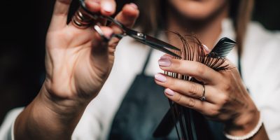 Close-up of a hairdresser cutting woman’s hair.